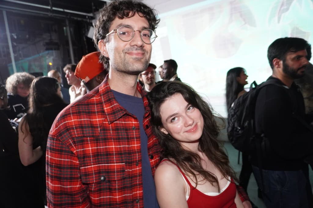 Two attendees posing together, flash-lit party scene.
