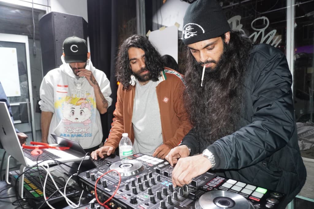Three people at the DJ booth with controller and laptop.